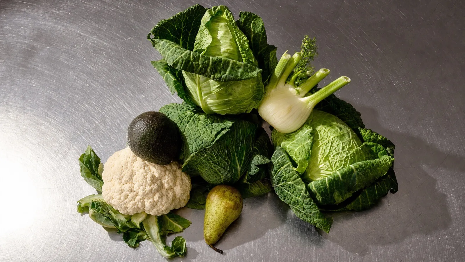 Blumenkohl, Wirsing, Fenchel, Avocado und eine Birne auf einer Stahlplatte