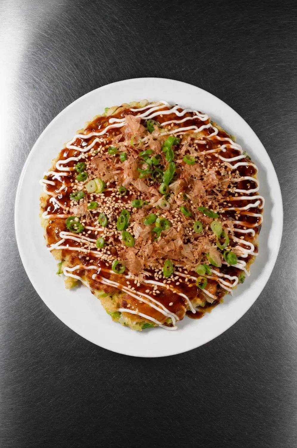 Okonomiyaki, von oben fotografiert auf einem weißen Teller